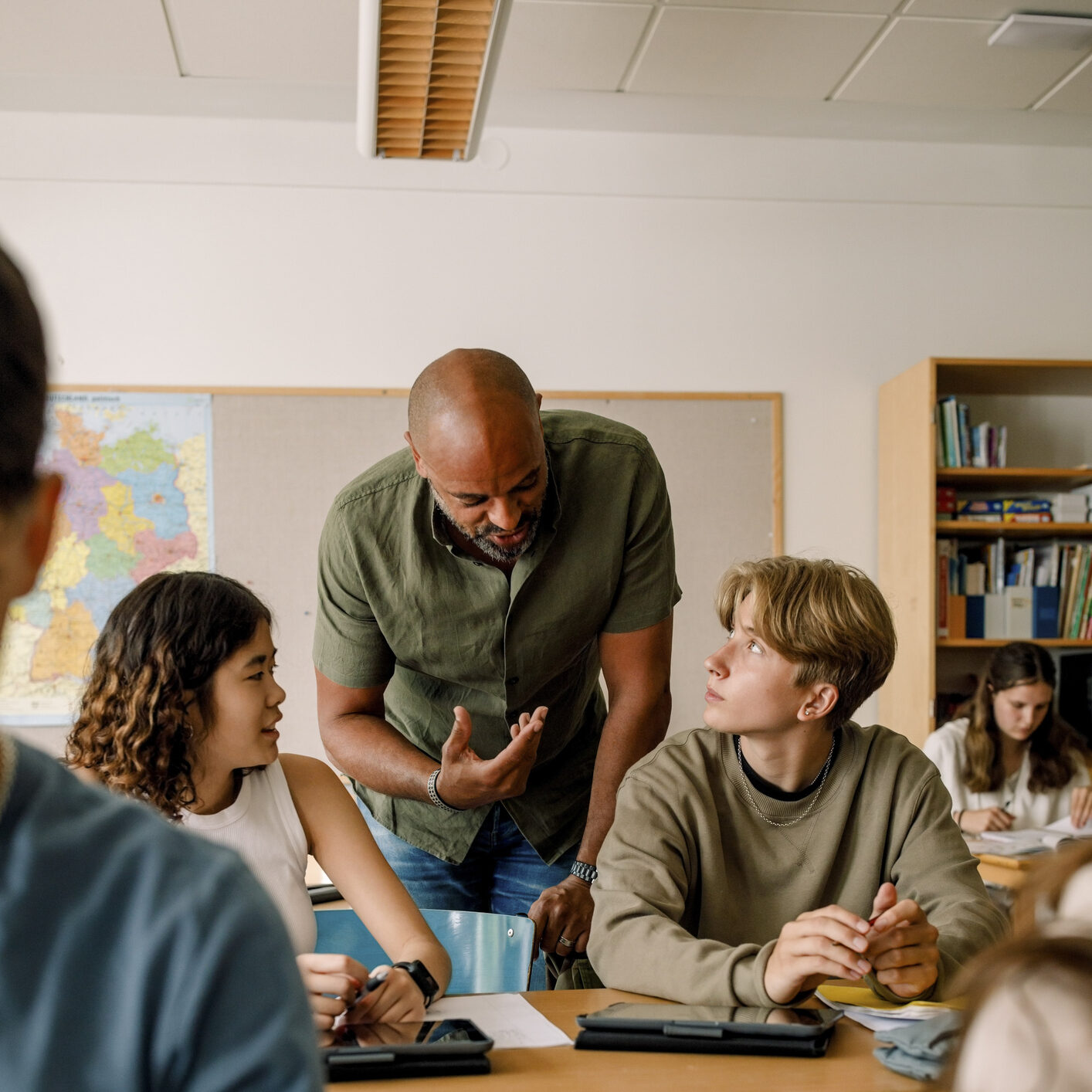 Teacher in a classroom talking to two students.